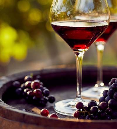 Rotweingläser auf Weinfass inmitten eines Weinguts im Sonnenuntergang